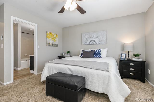 Bedroom with white bedding, blue accent pillows, a black leather bench, and an adjoining bathroom.