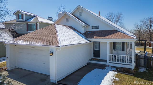 White-sided house with an attached garage and covered porch, with snow on the roof and driveway.