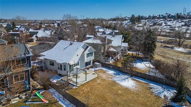 Aerial view of a suburban home with a fenced backyard, patio, and small pool amid snow-dusted homes.