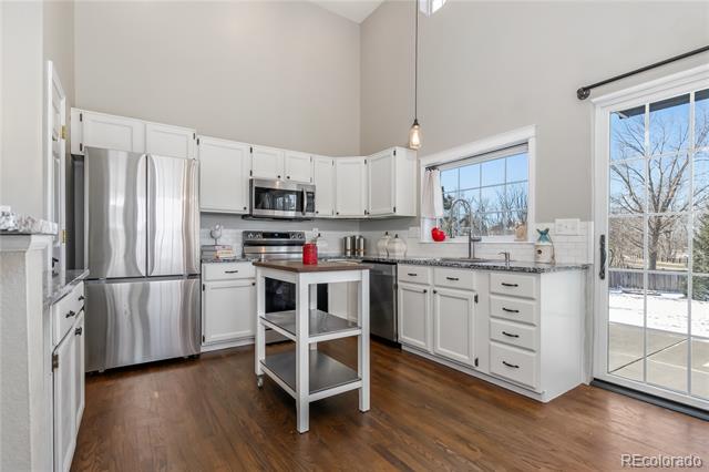 Kitchen with white cabinetry, stainless steel appliances, a center island, and sliding glass doors to a snowy yard.