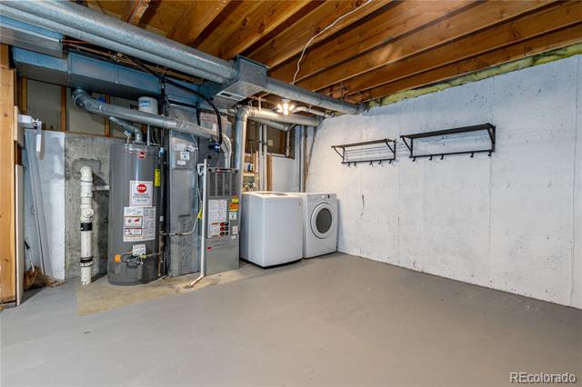 Basement laundry room with a water heater, furnace, and white washer and dryer.
