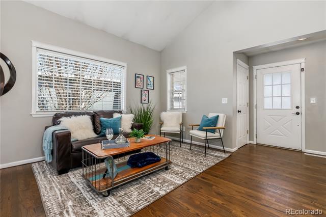 Staged living room with a leather sofa, patterned rug, and white front door.