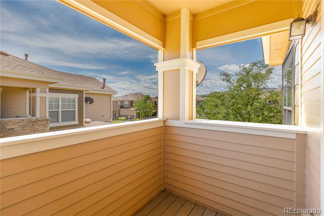 Covered balcony with wood-plank flooring and views of trees and neighboring homes.
