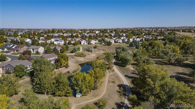 Aerial neighborhood view with a small pond, walking paths, and open space among homes.