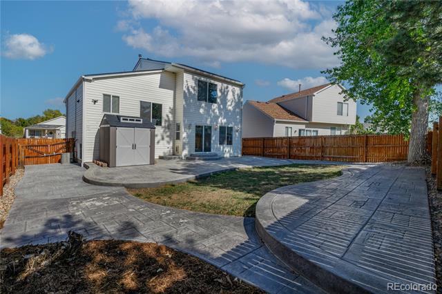 Rear of a white two-story house with a garage and broad curved concrete patio.