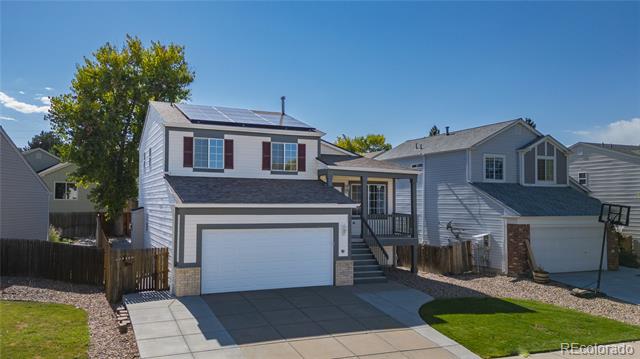 Two-story home with rooftop solar panels, an attached garage, and a wide driveway.