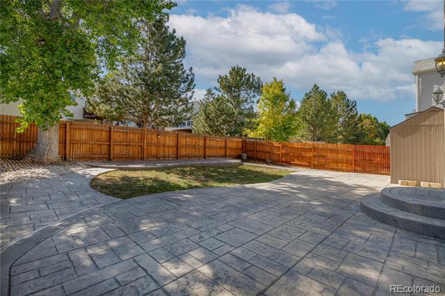 Backyard patio with stamped-concrete paving, a curved garden bed, and a wooden privacy fence.