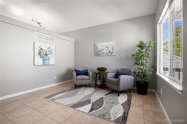 Sitting area with gray armchairs, a patterned rug, and a large window.