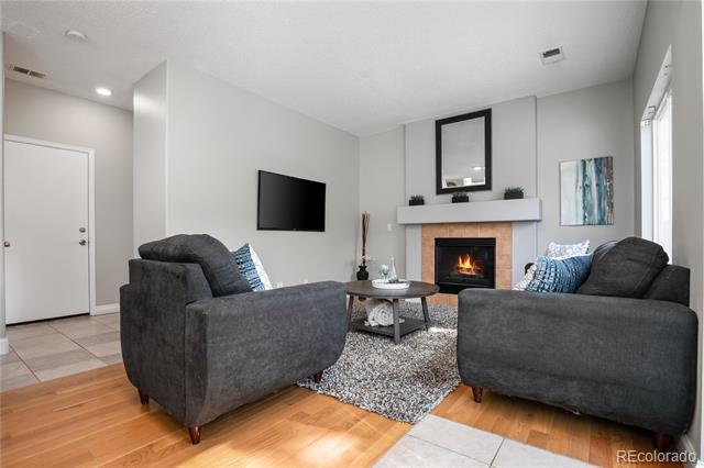 Living room with gray sofas, a lit fireplace, wall-mounted television, and patterned rug.