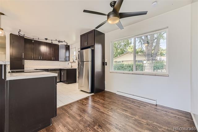 Kitchen and dining area with dark cabinets, stainless appliances, wood floors, and a large window.