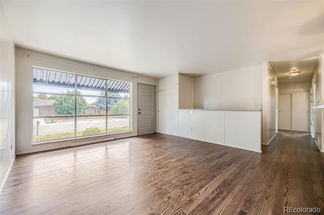 Vacant living area with dark hardwood floors, a large window, and a half-height kitchen counter.