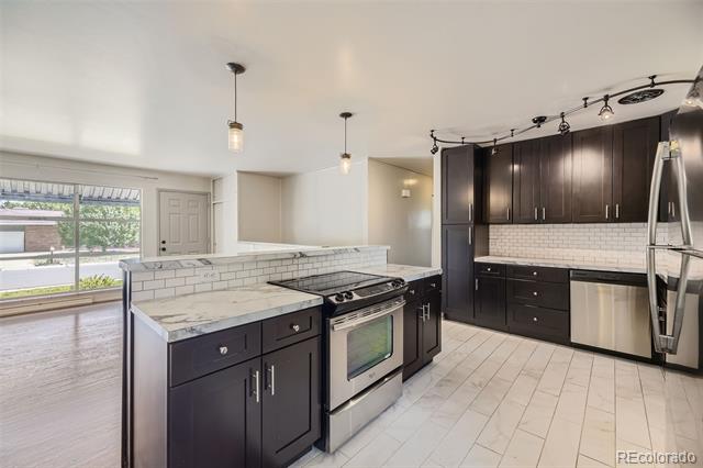 Open kitchen with dark cabinets, white tile backsplash, and a central island with a stainless steel range.
