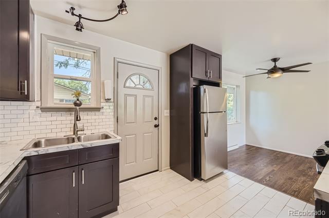 Kitchen with dark cabinets, stainless steel appliances, a tiled floor, and a window over the sink.