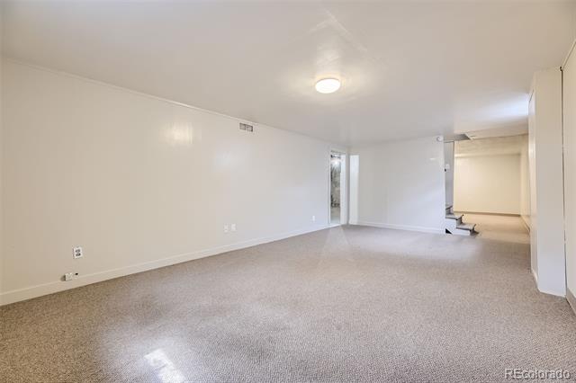 Vacant carpeted living room with a ceiling light and an adjoining recessed area.