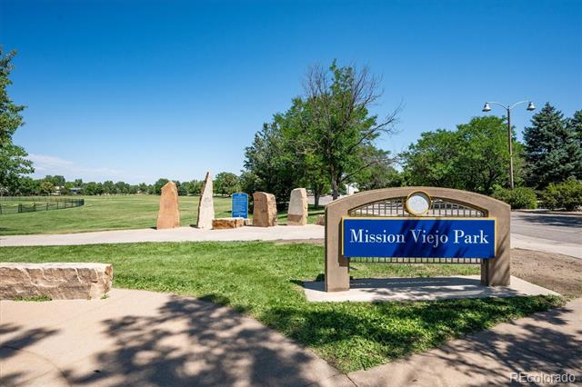 Mission Viejo Park entrance sign beside a paved path and open grassy fields.
