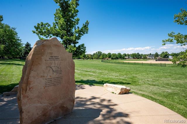Open grassy park with a stone monument beside a paved walkway.