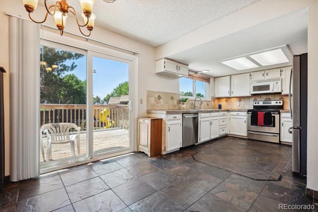 Kitchen with white cabinets and tiled floors, opening through sliding glass doors to a deck.