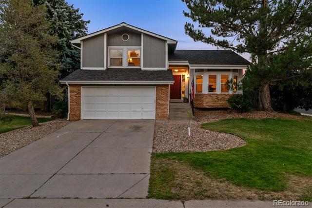 Two-story brick and gray house with an attached garage and red front door at dusk.