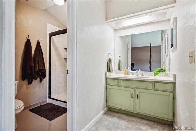 Bathroom with a pale green double vanity, wide mirror, and an adjoining toilet and shower area.