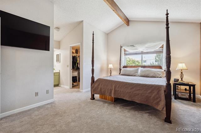 Bedroom with a four-poster bed, vaulted ceiling, exposed beam, and wall-mounted television.