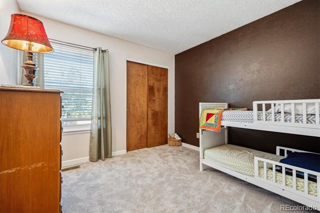 Bedroom with white bunk beds, a wooden closet, and a window with blinds.