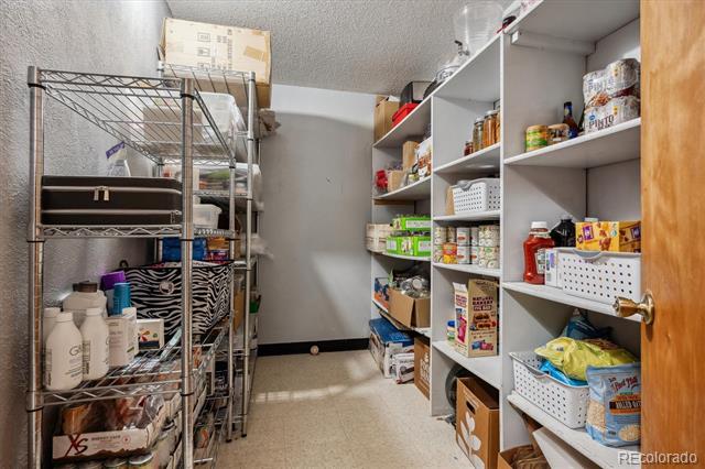 Walk-in pantry with stocked shelves and a metal wire storage rack.
