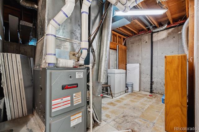 Basement mechanical room with an Amana furnace, exposed ductwork, and unfinished concrete walls.