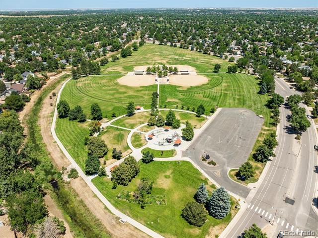 Aerial view of a neighborhood park with baseball diamonds, winding paths, and a large parking lot.