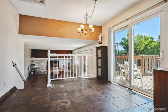 Open living area with stone tile floors, chandelier, fireplace, and sliding doors to a deck.