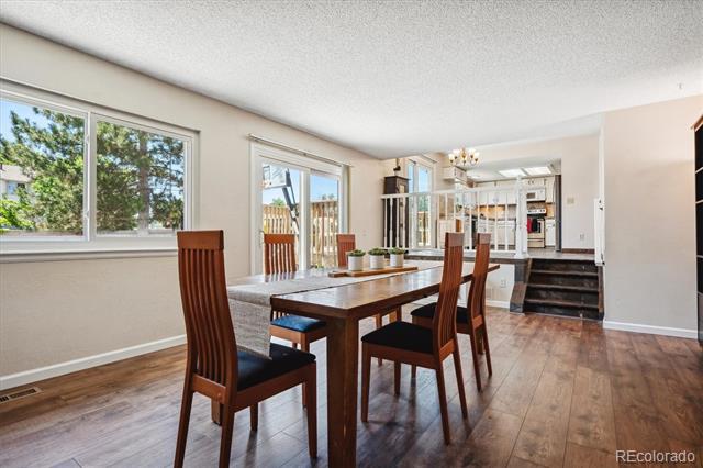Dining area with a dark wood table, hardwood floors, and an open view into the kitchen.