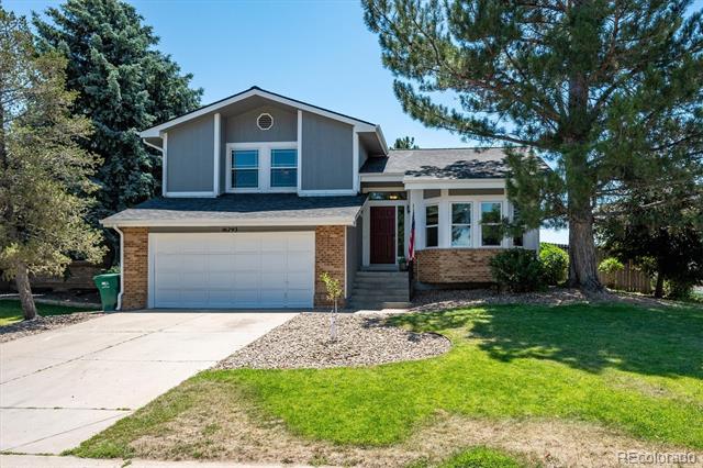 Two-story gray-and-brick house with a double garage, broad driveway, and mature trees.