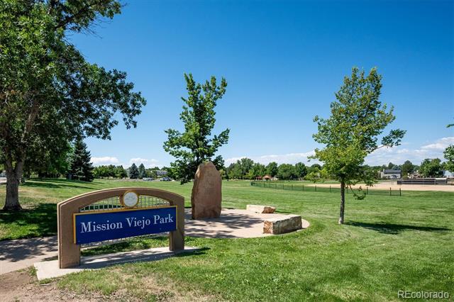 Mission Viejo Park sign beside a stone monument and open grassy lawn.