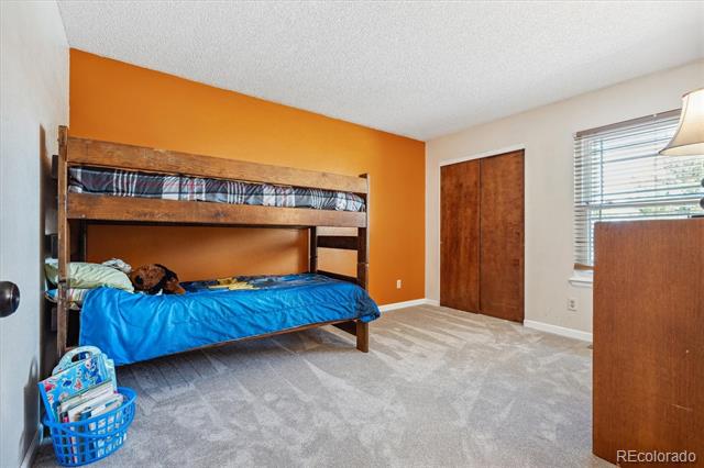 Bedroom with a wooden bunk bed, blue bedding, and an orange accent wall.