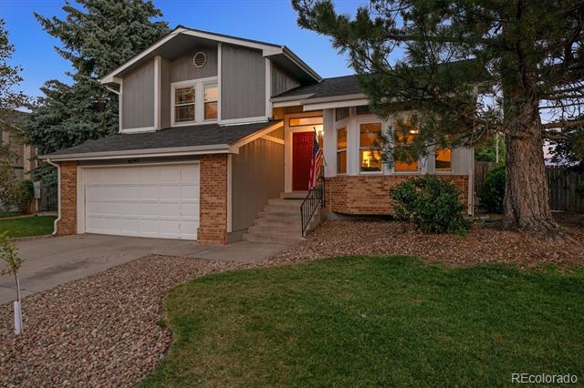 Two-story home with an attached garage, brick facade, and red front door at dusk.