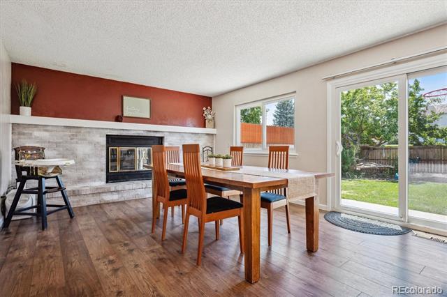 Dining room with a wood table, stone fireplace, red accent wall, and sliding doors to the yard.