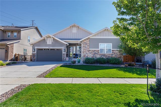 Single-story gray home with stone accents, an attached garage, and a broad green front lawn.