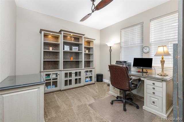 Home office with built-in shelving and a desk beside two windows with blinds.