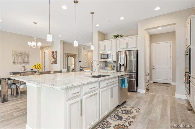 Open-plan kitchen with a large stone-topped island, white cabinetry, and stainless steel appliances.