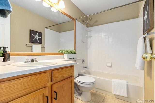 Bathroom with a wood vanity, large mirror, and white tub-shower combination.