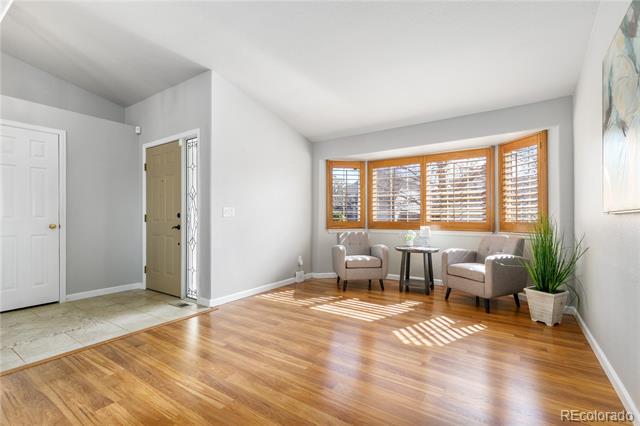 Living room and entry with hardwood floors, wood-framed windows, and two armchairs.