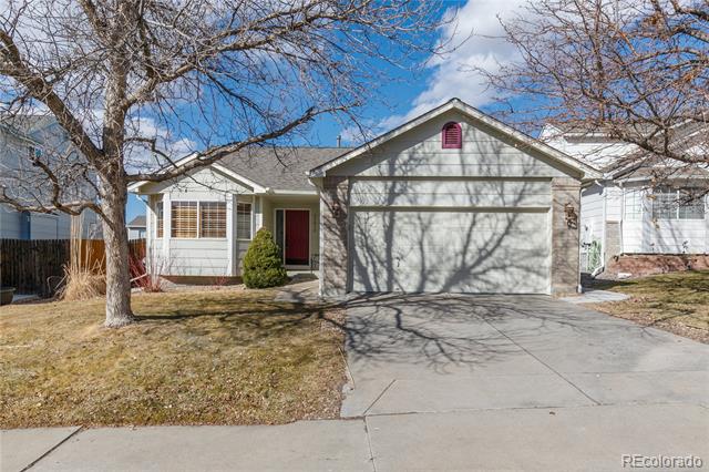 Single-story house with a two-car garage, red front door, and bare trees framing the driveway.