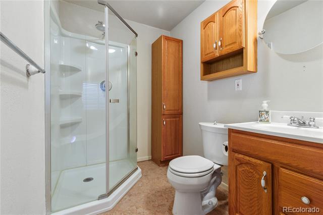 Bathroom with a glass corner shower, built-in shelves, and a wood vanity and cabinets.