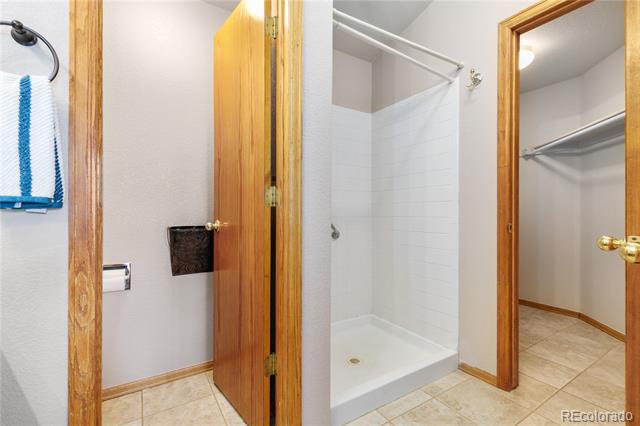Bathroom with a white-tiled shower beside an open closet.
