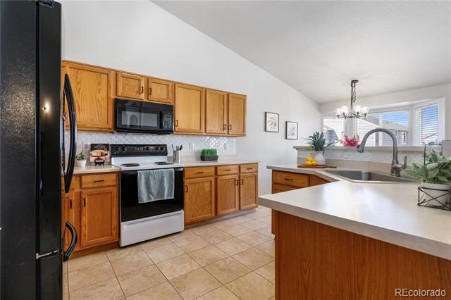 Kitchen with honey-toned wood cabinets, stainless steel appliances, and a large white-countertop peninsula.