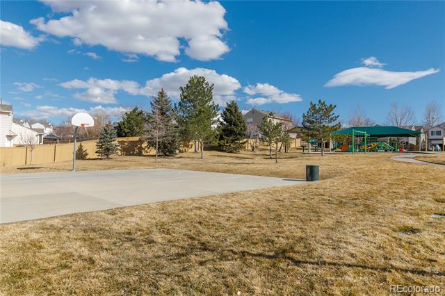 Neighborhood park with a basketball court, playground, and open grassy area.