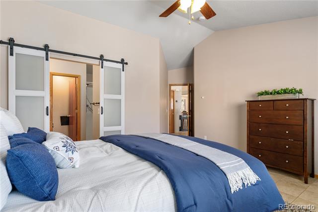 Bedroom with blue and white bedding, sliding barn doors, and a wooden dresser.
