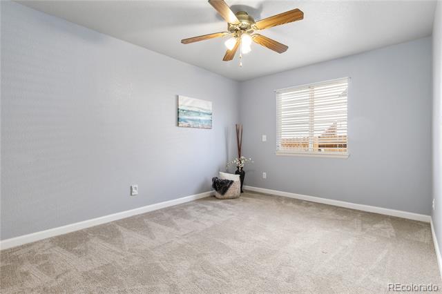 Carpeted room with a wooden ceiling fan, window blinds, and sparse decor.
