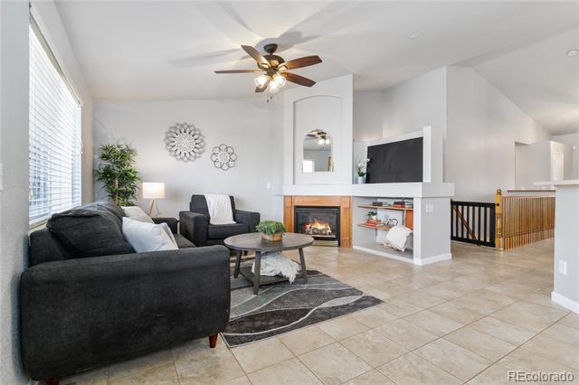 Living room with dark sectional, tiled floor, and white fireplace beneath a television.
