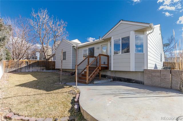 Home exterior with a raised wooden entry deck, concrete driveway, and fenced yard.