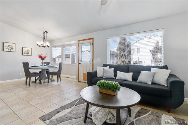 Furnished living and dining area with a dark sofa, tiled floors, and large windows.